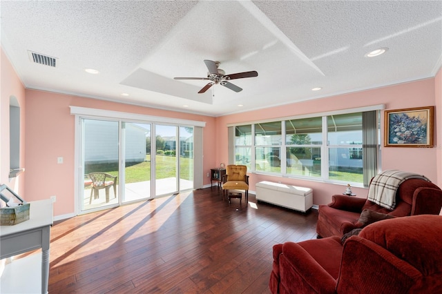 living area with a textured ceiling, hardwood / wood-style flooring, recessed lighting, visible vents, and baseboards