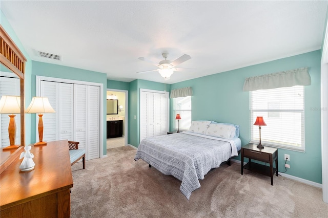 bedroom with a ceiling fan, visible vents, baseboards, carpet, and two closets