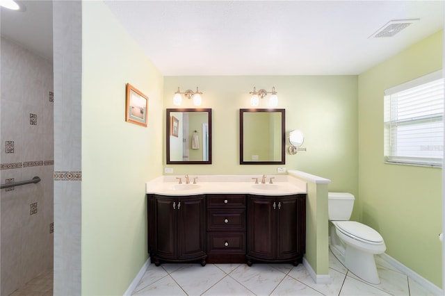 full bathroom with toilet, double vanity, visible vents, and a sink