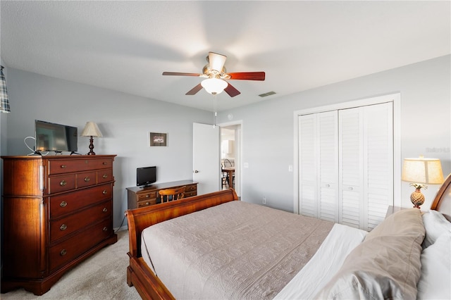 bedroom with a ceiling fan, visible vents, a closet, and light colored carpet