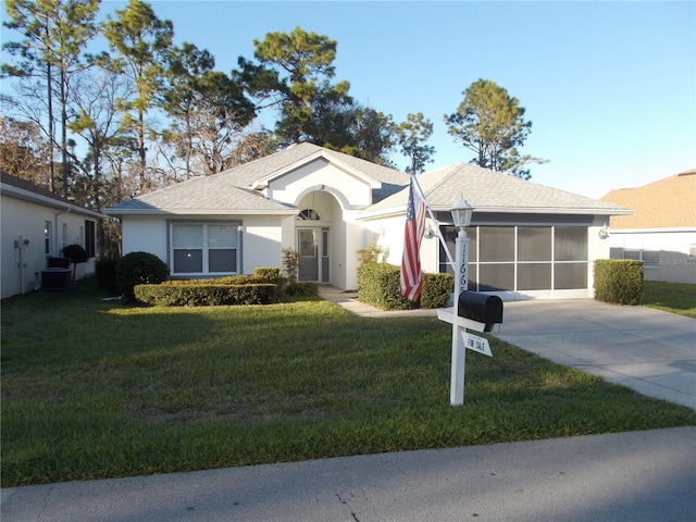 single story home with stucco siding, a sunroom, a garage, driveway, and a front lawn