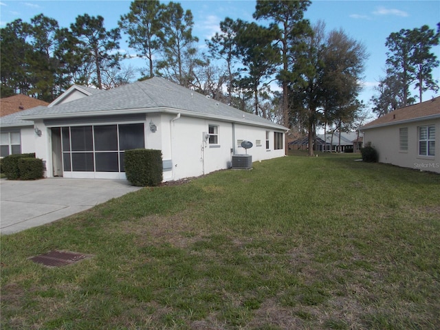 view of property exterior with an attached garage, cooling unit, a yard, concrete driveway, and stucco siding