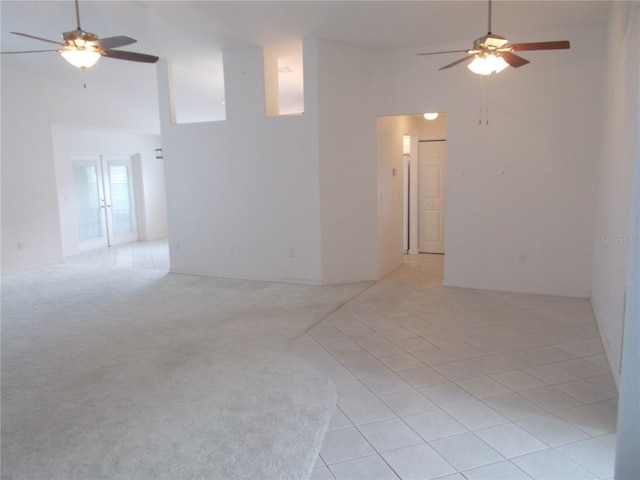 spare room featuring high vaulted ceiling, light colored carpet, ceiling fan, and light tile patterned floors