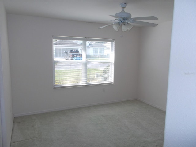 carpeted spare room with a ceiling fan and baseboards