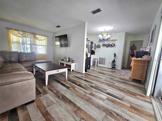 living area with visible vents, a notable chandelier, and wood finished floors