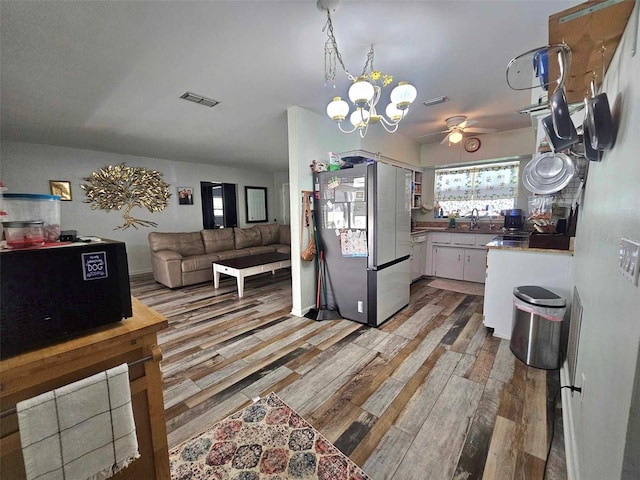 kitchen with pendant lighting, visible vents, light wood-style floors, freestanding refrigerator, and white cabinetry