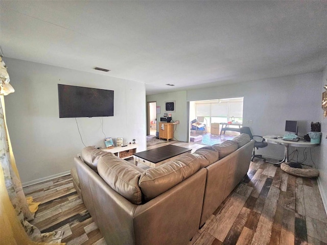 living room with wood finished floors, visible vents, and baseboards