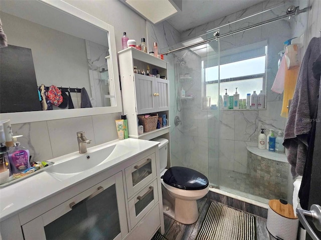 bathroom featuring vanity, wood finished floors, a marble finish shower, and toilet