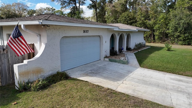 view of front of house featuring a garage, a front yard, driveway, and stucco siding