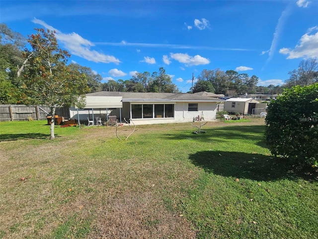 back of property with a carport, a yard, and fence