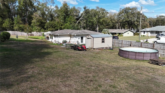 rear view of house featuring a fenced in pool, an outbuilding, a lawn, fence, and a shed