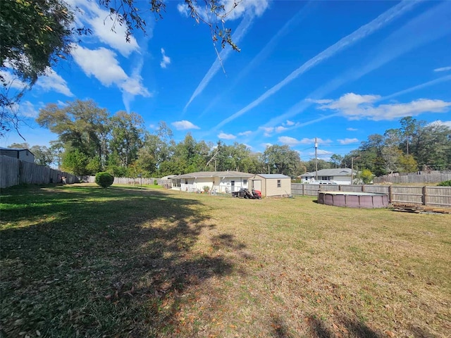 view of yard featuring a fenced backyard, an outdoor structure, and a storage unit