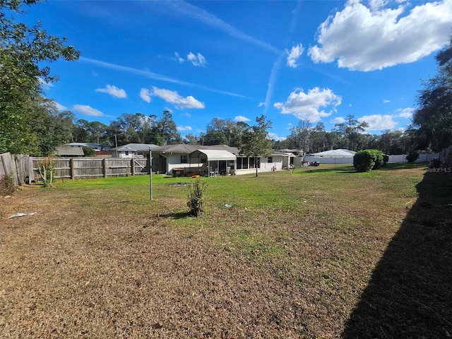 view of yard featuring a sunroom, a fenced backyard, and a carport