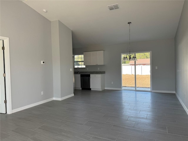 unfurnished living room featuring a chandelier, a wealth of natural light, visible vents, and baseboards