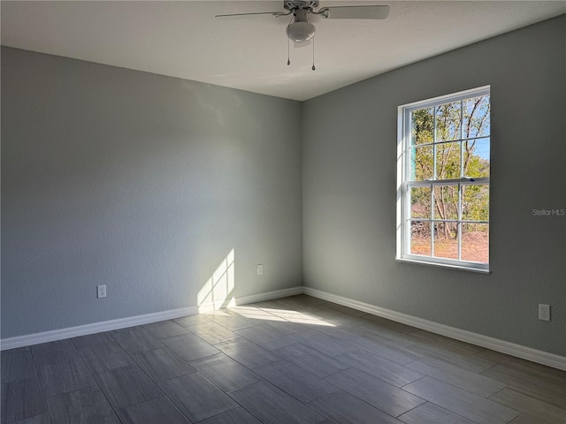 spare room featuring a ceiling fan, dark wood finished floors, and baseboards