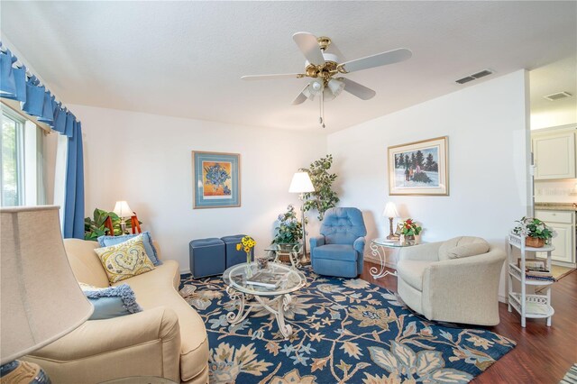 living room featuring ceiling fan, visible vents, and wood finished floors