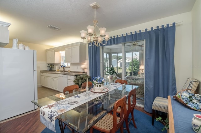 dining room featuring visible vents, a chandelier, a textured ceiling, and wood finished floors