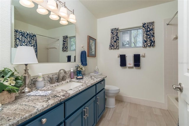 bathroom with toilet, vanity, a wealth of natural light, and baseboards