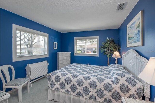 carpeted bedroom featuring visible vents and a textured ceiling