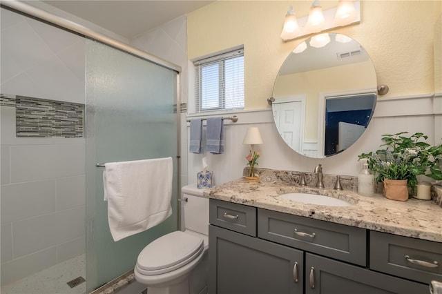 bathroom with toilet, visible vents, a shower stall, and vanity