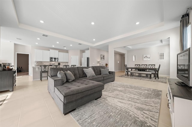 living area with light tile patterned floors, a raised ceiling, and recessed lighting