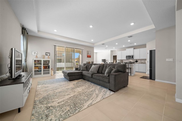 living room with recessed lighting, a raised ceiling, baseboards, and light tile patterned floors