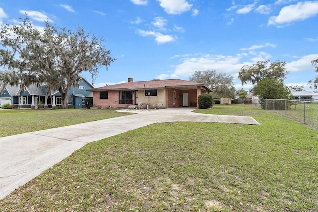 view of front of property featuring brick siding, fence, concrete driveway, a chimney, and a front yard