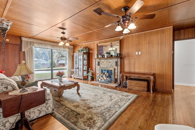 living area with wood walls, a fireplace, wood ceiling, and hardwood / wood-style flooring