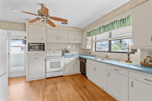 kitchen featuring white electric range oven, black dishwasher, white cabinets, light wood-type flooring, and a sink