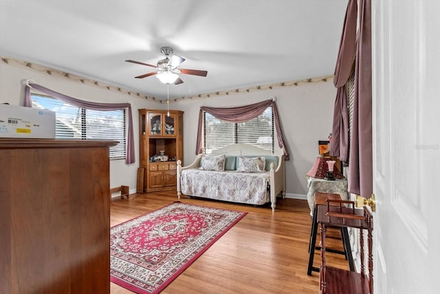 bedroom with baseboards, a ceiling fan, and light wood-style floors