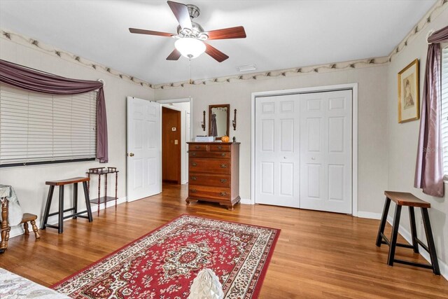 living area featuring ceiling fan, visible vents, baseboards, and wood finished floors