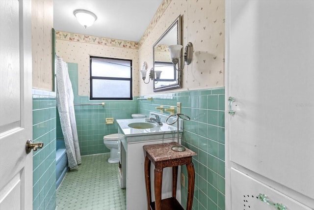 full bathroom with tile patterned flooring, toilet, vanity, wainscoting, and wallpapered walls