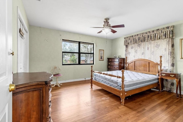 bedroom with light wood-type flooring, a ceiling fan, and baseboards