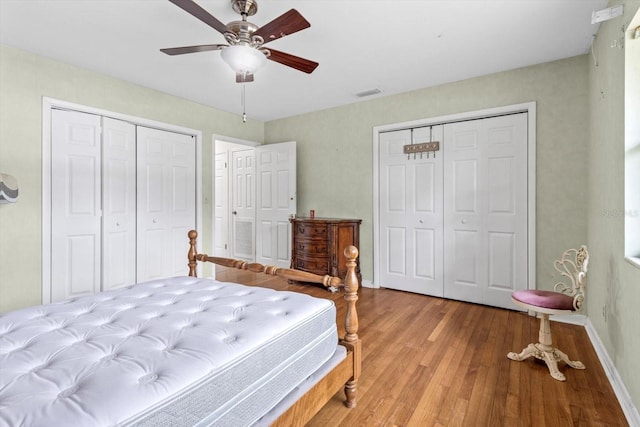 bedroom with baseboards, ceiling fan, visible vents, and wood finished floors