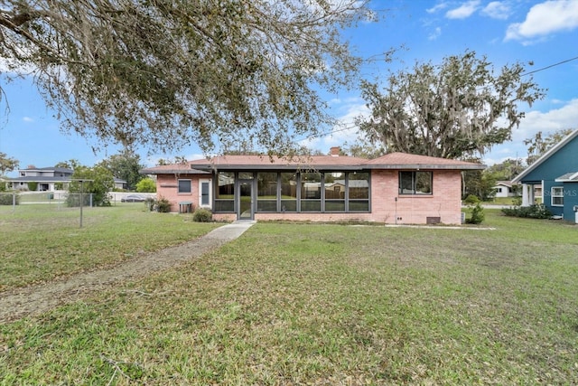 back of property with brick siding, fence, and a yard