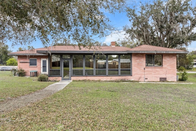 view of front facade with crawl space, a chimney, a front lawn, and brick siding