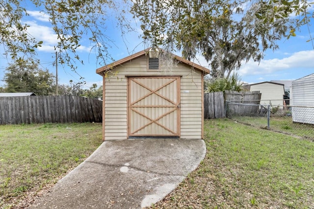 view of shed with a fenced backyard and concrete driveway