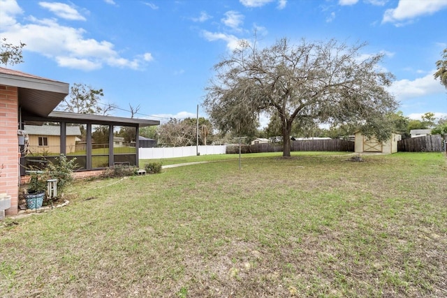 view of yard featuring a sunroom, a fenced backyard, a storage unit, and an outdoor structure