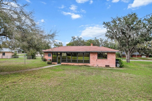 back of property featuring brick siding, a lawn, a chimney, and fence