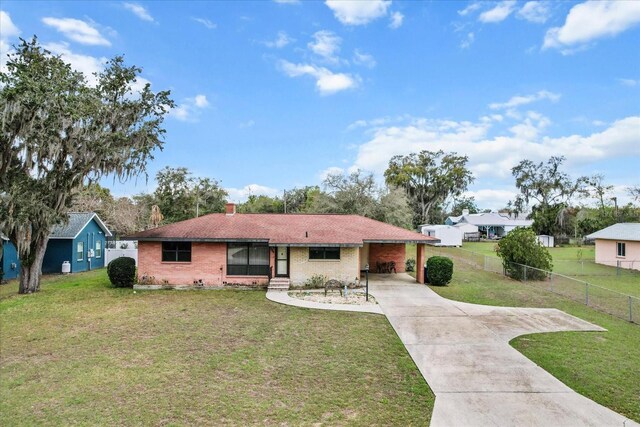 ranch-style house featuring driveway, a front lawn, an attached carport, and brick siding