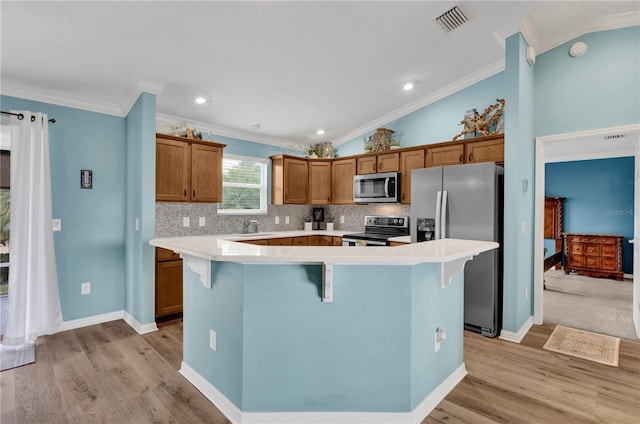 kitchen featuring crown molding, stainless steel appliances, visible vents, vaulted ceiling, and a kitchen bar