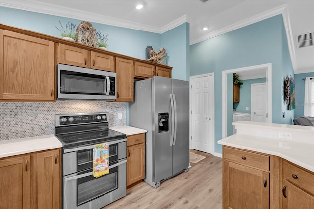 kitchen featuring appliances with stainless steel finishes, decorative backsplash, crown molding, and washer and dryer