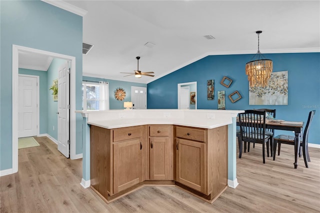 kitchen featuring crown molding, lofted ceiling, visible vents, and light wood-style floors