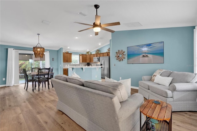 living room with crown molding, vaulted ceiling, light wood-type flooring, baseboards, and ceiling fan with notable chandelier