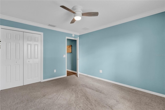 unfurnished bedroom with ornamental molding, a closet, carpet, and baseboards