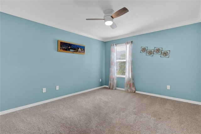 spare room featuring carpet floors, crown molding, baseboards, and a ceiling fan