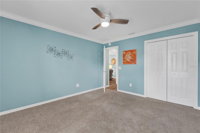 unfurnished bedroom featuring carpet floors, crown molding, a closet, a ceiling fan, and baseboards