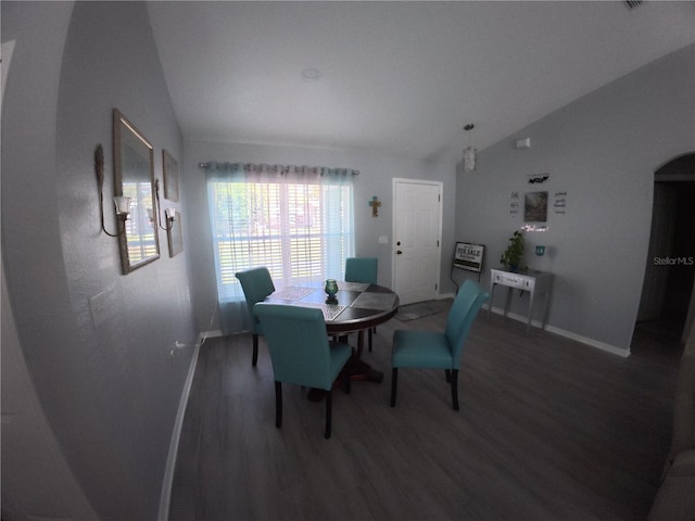 dining space with lofted ceiling, wood finished floors, and arched walkways