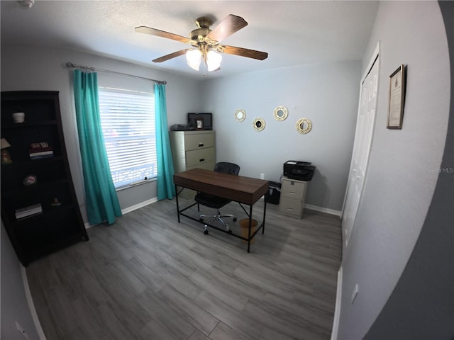 office featuring wood finished floors, a ceiling fan, and baseboards