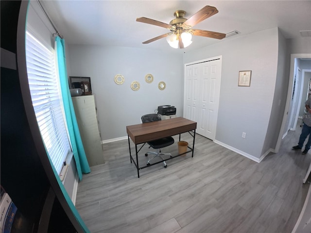 office space with a ceiling fan, visible vents, baseboards, and wood finished floors